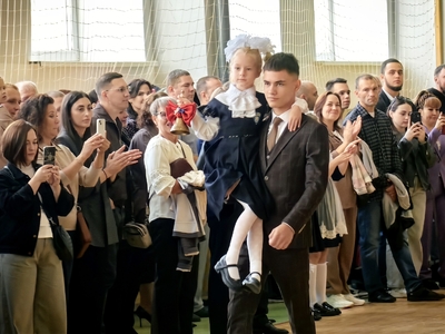 Первый звонок одиннадцатиклассник несет на плечах первоклассницу 